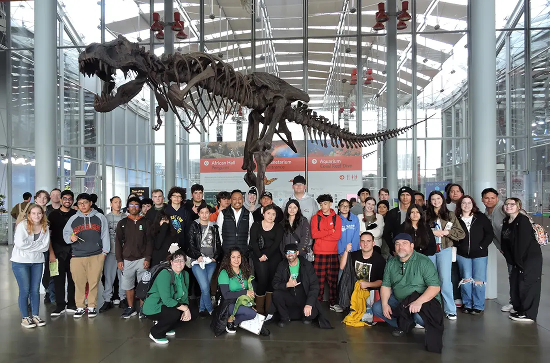 Science Trip picture of students and staff under the skeleton of a T-Rex